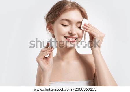 Girl cleaning face with cotton sponge. Beautiful model with shiny clean skin. Isolated on white background