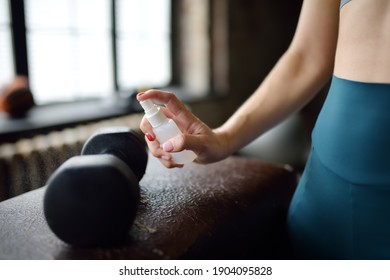 Girl cleaning of sport equipments of gym with disinfecting spray. Woman making disinfection of dumbbells with sanitizer during epidemic. Protection and prevention from infection disease - Powered by Shutterstock