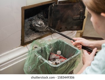 Girl Cleans The Fireplace. Shovel With Ash Is Taken Out Of The Fire . Woman Doing House Work