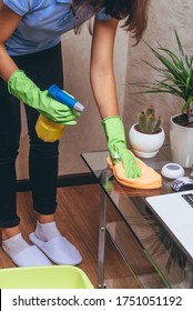 The girl cleans the glass table with detergent and wipes the cloth. Chemistry will spray from the bottle. Cleaning the house in quarantine. Cleaning of the apartment. Blue T-shirt. Experienced worker - Shutterstock ID 1751051192
