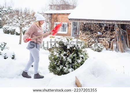 The girl cleans the snow in the country. Work in the garden in winter.