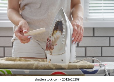 The girl cleans the sole of the iron with a special cleaning pencil, cleaning the iron from carbon deposits, close-up - Shutterstock ID 2012625209