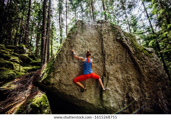 girl climbing hard boulder problem in forest.
Sport climbing,
bouldering.