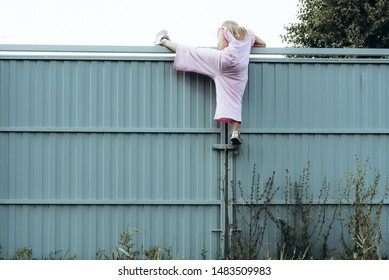 Girl climbing metal fence outdoor. Curious child on high white painted gates. Naughty kid playing outside, breaking rules. Childhood and youth concept. Restless teen entering private property - Shutterstock ID 1483509983