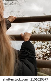 A Girl Climbing  On Outdoor Artificial Wooden Boulder Without Safety Belts. She Wears Hat. Reaching The Goal, Making An Effort Concept Photo. Her Face Doesn't Visible In Photo. 