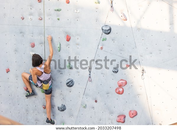 the\
girl climbs on the climbing wall. rock climbing as a type of active\
recreation in the city. playing sports in\
nature.\
