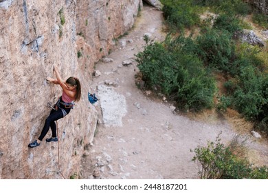 The girl climbs the rock. The climber is training to climb the rock. A strong athlete overcomes a difficult climbing route. Extreme hobby. A woman goes in for sports in nature. Natural rocky terrain.
 - Powered by Shutterstock