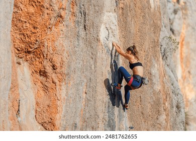 The girl climbs the rock. The climber is training to climb the rock. A strong athlete overcomes a difficult climbing route. Extreme hobby. A woman goes in for sports in nature. 
 - Powered by Shutterstock