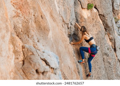 The girl climbs the rock. The climber is training to climb the rock. A strong athlete overcomes a difficult climbing route. Extreme hobby. A woman goes in for sports in nature. 
 - Powered by Shutterstock