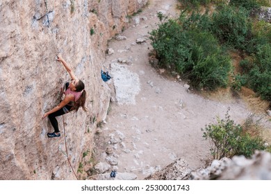 The girl climbs the rock. The climber is training to climb the rock. A strong athlete overcomes a difficult climbing route. Extreme hobby. A woman goes in for sports in nature. Natural rocky terrain.
 - Powered by Shutterstock