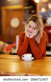Mädchen mit geschlossenen Augen sitzend am Tisch mit Tasse Kaffee in einem Café. Langsamer Fokus.