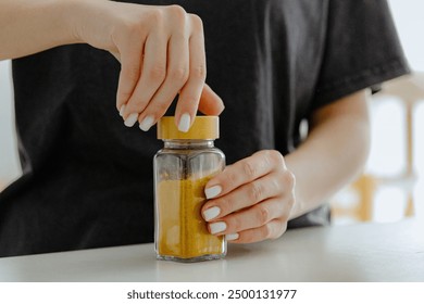 The girl closes the lid on a jar of spices. - Powered by Shutterstock