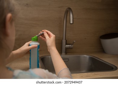 Girl Closing The Pet Water Bottle After Filling It At The Kitchen Tap. Selective Depth Of Field, Only Water Bottle And Closing Hand In Focus, Rest Of The Picture Is Out Of Focus.