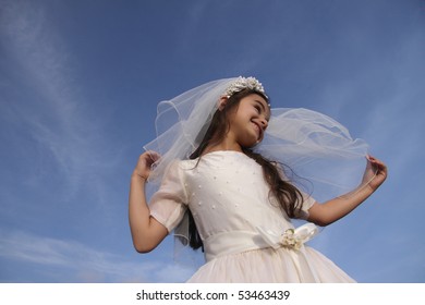 Girl In Communion Dress Against Blue Sky