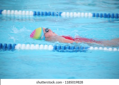 Girl competitive swimmer races during a swim meet in swimming pool backstroke - Powered by Shutterstock