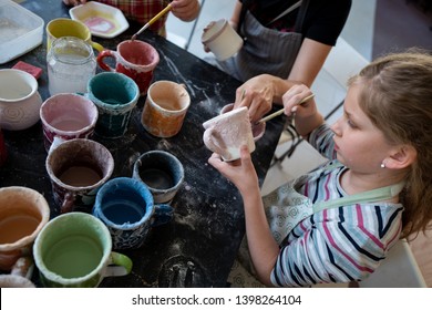 Girl Concentrating On Painting Pottery