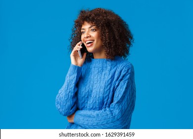 Girl Congratulating Family With Happy Holidays, Wishing Well New Year As Talking On Phone From Abroad, Holding Smartphone Speaking, Calling Friend, Looking Left And Smiling, Blue Background