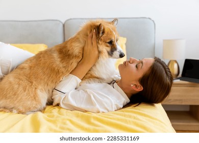 girl with corgi dog on the bed hugs and kisses ,dog man friend. High quality photo - Powered by Shutterstock