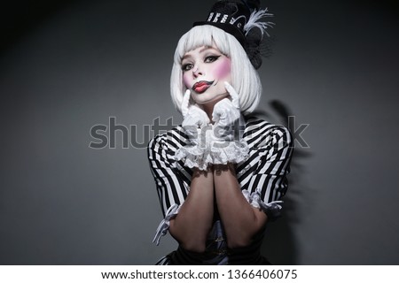 Girl in costume for Halloween holding.Sexy female in dress on gray background. Happy Halloween on the World. Holiday clown.