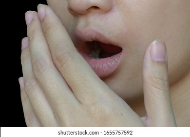 a girl covering her mouth because of  mouth odour - bad breath isolated on black