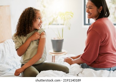 Girl With Covid Vaccine Shows Mother Vaccinated Arm With Plaster As Covid19 Protection For A Kid In A Bedroom Home. Child After Getting An Injection Bonding With Her Mom In The Bedroom