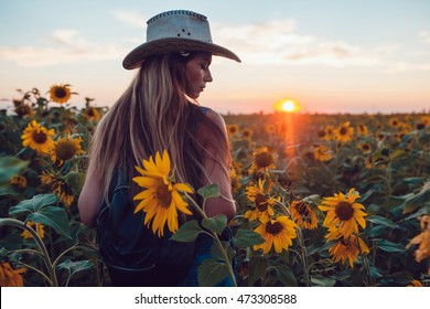 Girl In A Cowboy Hat In A Sunflower Field. Sunset