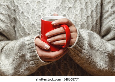 The Girl In A Cozy Knitted Sweater Drinking Coffee From A Red Mug