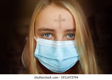 Girl with cross made from ash on forehead with face mask. Ash wednesday concept.