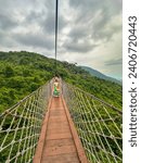 A girl is crossing the rope bridge in  Yalong Bay Tropical Paradise Forest Park.