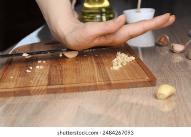 A girl crushes garlic with a knife. Preparation of garlic aromatic butter. - Powered by Shutterstock