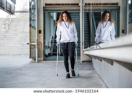 girl with crutches walking alone, head-on. Woman with crutches