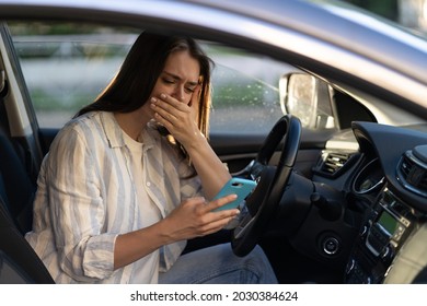 Girl Cry Reading Message In Mobile Phone. Frustrated Upset Young Woman In Tears Sit At Driver Seat In Car With Smartphone In Hand. Female Get Bad News, Breaking Up With Boyfriend In Text Sms Messenger