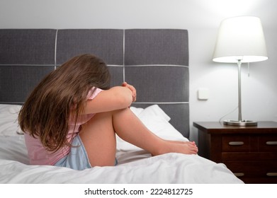 Girl Crying In Tears Sitting On Bed In Bedroom. Unhappy Children Feeling Sad Lonely And Upset In Dark Room At Night At Home. High Quality Photo