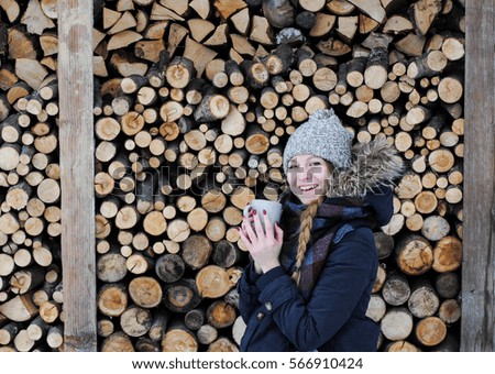 Girl with a cup of coffee in hand on the background of wood.Cup of coffee warms the girl from the cold.