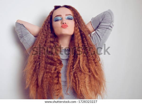 Girl with curled voluminous hair, model with\
hairstyle in the style of the 80s. 90s, with bright blue make-up.\
Hair care, brunette red-haired girl with long hair, curling curls,\
corrugation hair