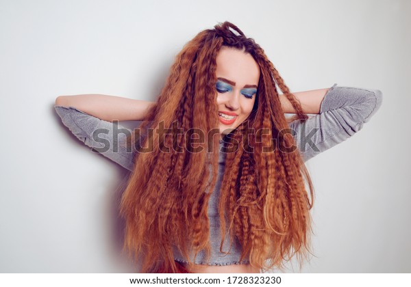 Girl with curled voluminous hair, model with\
hairstyle in the style of the 80s. 90s, with bright blue make-up.\
Hair care, brunette red-haired girl with long hair, curling curls,\
corrugation hair