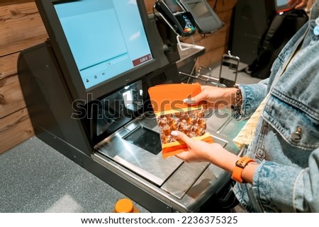 A girl customer scanns and pays for goods from a supermarket in an automated self-service checkout terminal