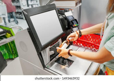 Girl customer scans bottle of wine at the self-service checkout in the grocery supermarket shop - Shutterstock ID 1493463932