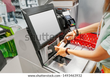 Girl customer scans bottle of wine at the self-service checkout in the grocery supermarket shop