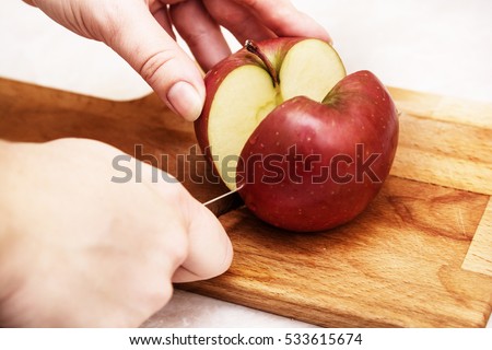 The girl is cutting apple on the cutting board