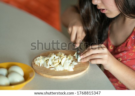 Girl cutting boiled eggs. Cooking healthy home meal. Female hands are cut boiled eggs at home in the kitchen for salad. On the table ingredients for salad, okroshka