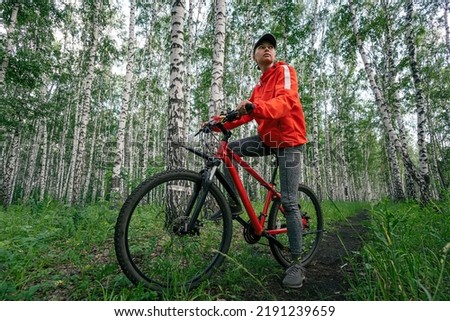 A girl cyclist is riding her road bike on the road in a beautiful thick green forest. Bikegirl in mystery forest.
