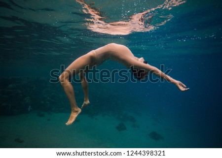 Girl dance under the water next to the reef