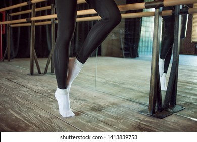 girl the dancer next to a ballet bar, Legs close up. young woman dancer warming up near the ballet Barre in the dance hall.