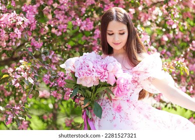 A girl dancing with a bouquet of pink peonies in a blooming garden - Shutterstock ID 2281527321