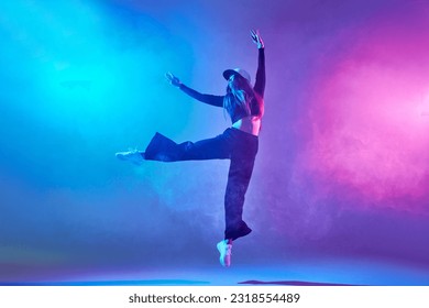 a girl in dark clothes dances on a neon background in smoke, modern dance - Powered by Shutterstock