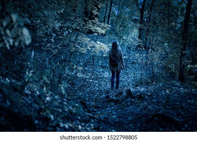 Girl In Dark Creepy Woods At Night. Brave Young Woman Walking Away Alone On Path Through Fantasy Spooky Forest. Lonely Person In Mystery Park, Back View. Fear In Scary Creepy Place On Halloween.