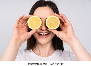 The girl with dark hair in white t-shirt put the eyes of two lemons, smiles, the concept of beauty and health.