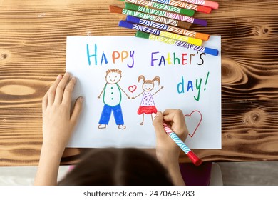 girl daughter draws a card to dad for Father's Day, drawing of dad and daughter on a white sheet with multi-colored felt-tip pens, concept of sweet wishes. - Powered by Shutterstock