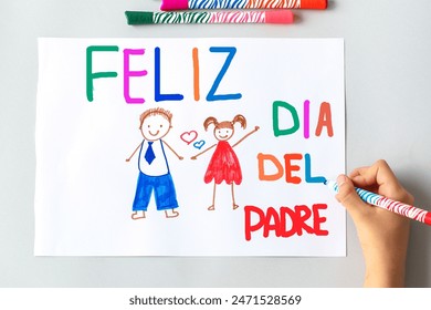 girl daughter draws a card to dad for Father's Day in Spanish, drawing of dad and daughter on a white sheet with multi-colored felt-tip pens, concept of sweet wishes. - Powered by Shutterstock